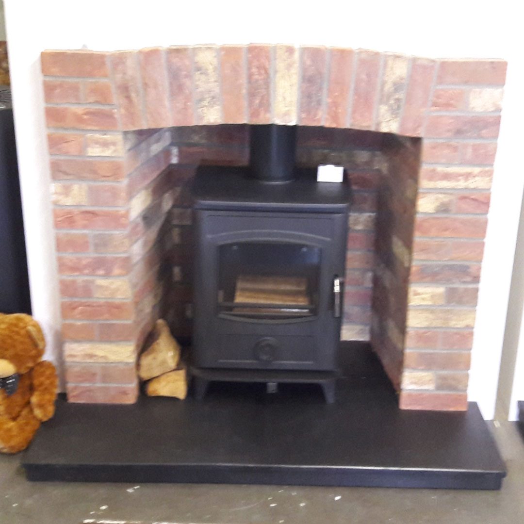 Multi fuel stove in brick inset with brick surround and black hearth