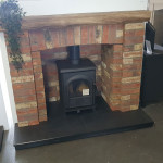 multi fuel stove in brick inset with brick surround and wooden mantle