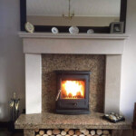 Multi fuel stove in marble inset and marble mantle with log storage