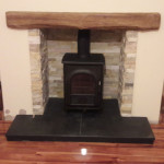 Multi fuel stove in slate inset with wooden mantle and black hearth